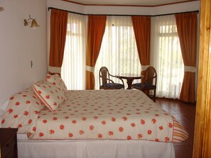 A bedroom with a bed, two chairs, and a small table.