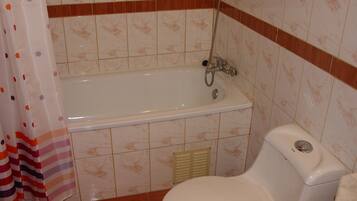 A bathroom with a bathtub, toilet, and shower curtain.