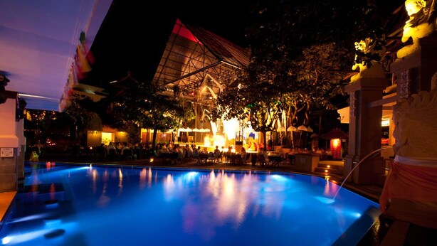 A pool area with a large, illuminated building in the background. - Bounty Hotel (Kuta)