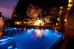 A pool area with a large, illuminated building in the background. - Bounty Hotel (Kuta)