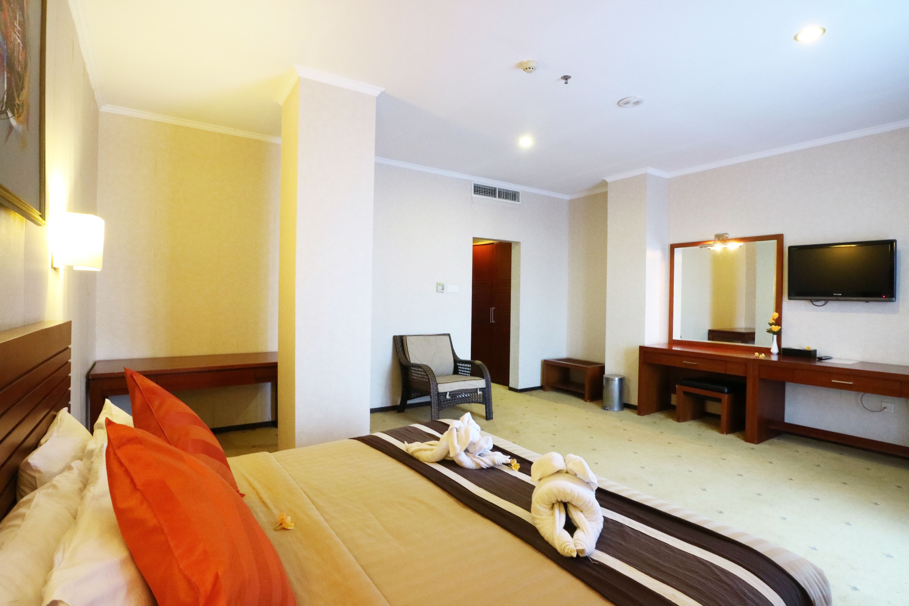 A hotel room with a bed, a desk, a chair, a television, and a bathroom door.