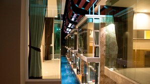 A modern hotel interior with a central atrium, glass railings, and a pool area. - P10 Samui (Koh Samui)