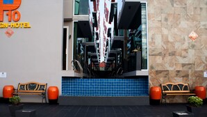 A hotel entrance with a modern design, featuring a blue tiled area, two wooden benches, and orange planters. - P10 Samui (Koh Samui)
