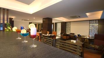 Eine moderne Bar mit einer Granitabdeckung, mehreren farbenfrohen Cocktails und einer Sitzecke mit Holztischen und -stühlen.