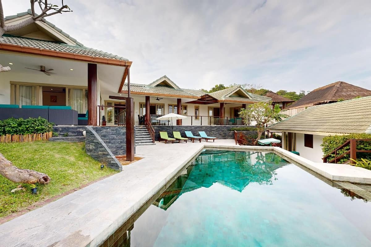A modern resort with a swimming pool, outdoor seating, and a covered patio area.