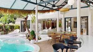 Un área de piscina moderna al aire libre con sillones de descanso, una mesa de comedor y un jacuzzi.