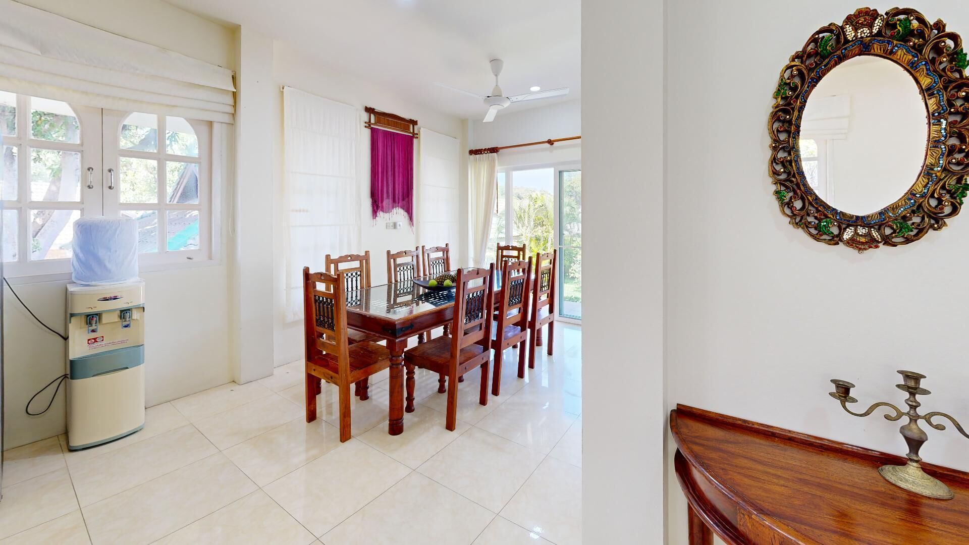 A dining area with a table and chairs, a water dispenser, and a decorative mirror.