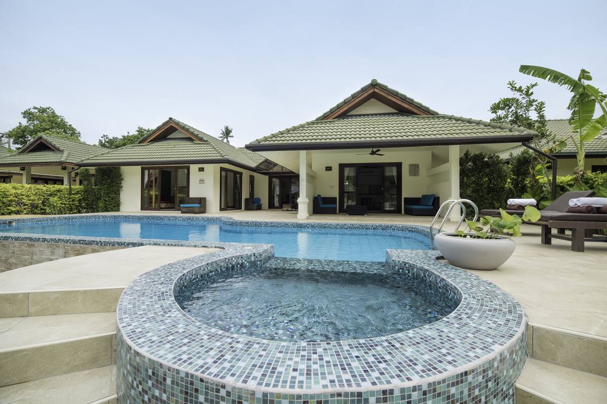A resort with a swimming pool, a hot tub, and lounge areas.