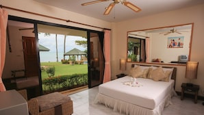 Un dormitorio con una cama grande, un escritorio y vistas a un jardín y al agua.