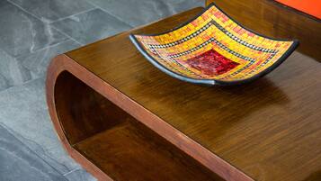 A wooden table with a colorful mosaic bowl on top.