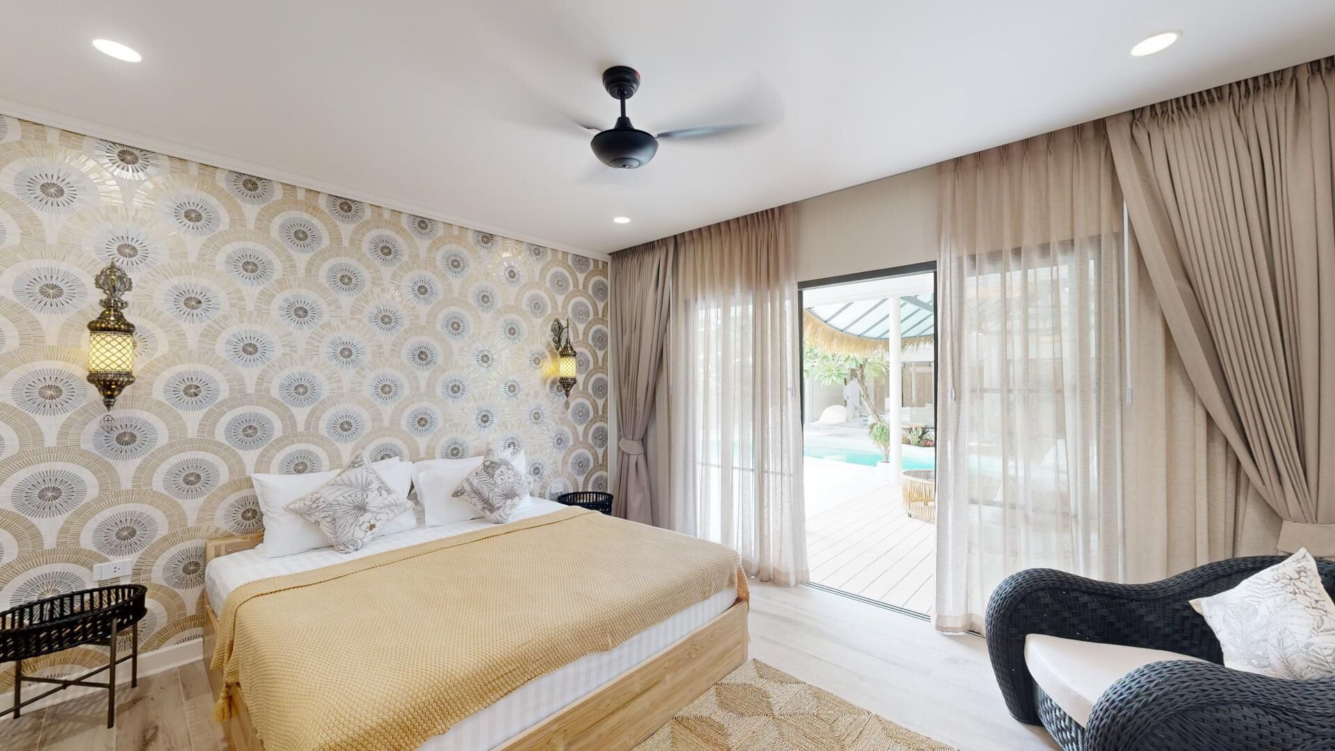 A bedroom with a bed, a chair, a ceiling fan, and a view of an outdoor pool.