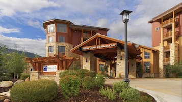 A hotel with a stone facade, a covered entrance, and a sign for the Hilton Grand Vacations Club.