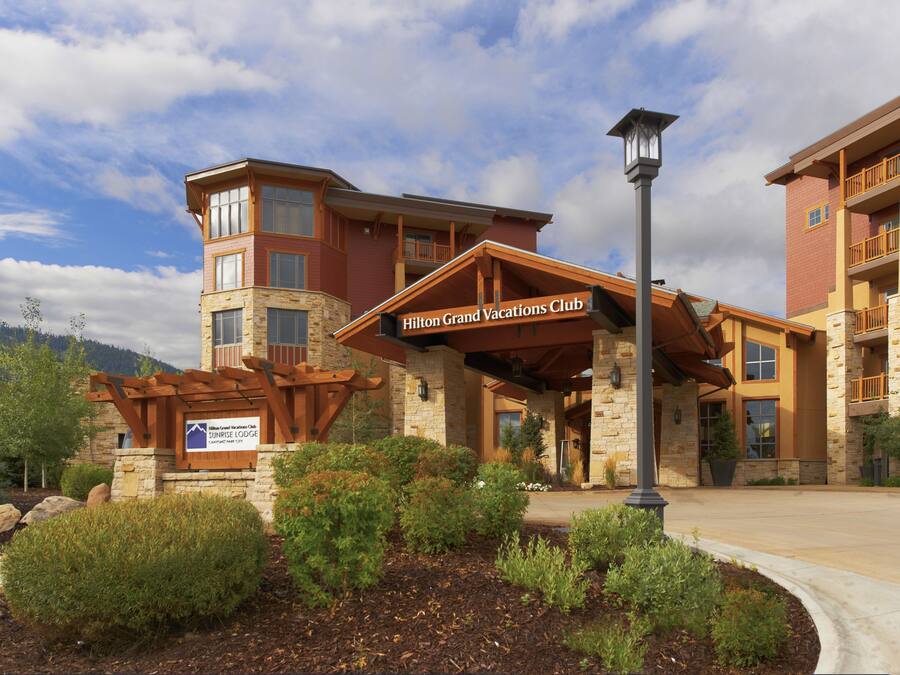 A hotel with a stone facade, a covered entrance, and a sign for the Hilton Grand Vacations Club.
