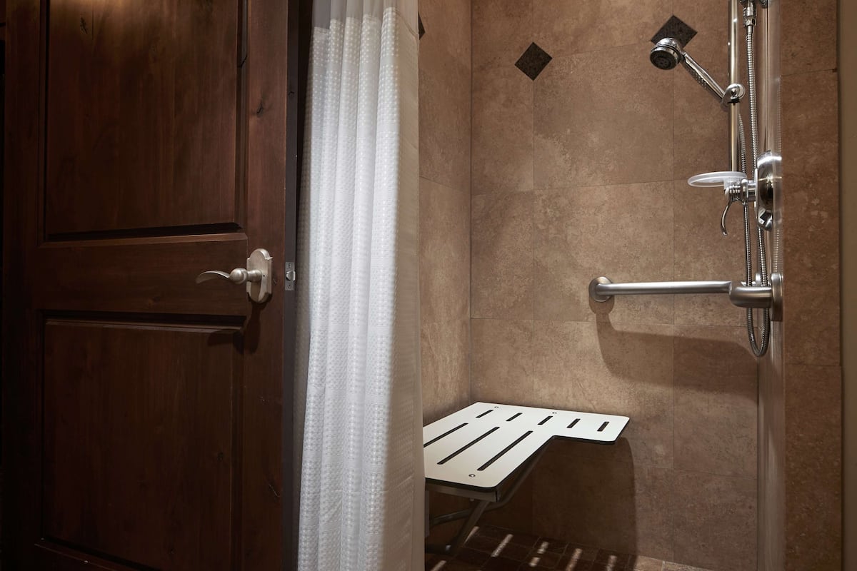 A shower area with a handheld showerhead, a handheld shower attachment, and a wall-mounted faucet.