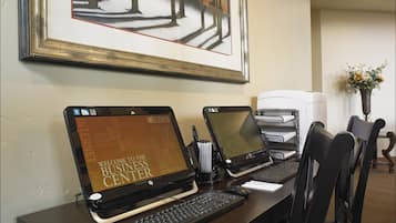 Un centro de negocios con dos portátiles HP, un teclado, un ratón y una impresora sobre un escritorio.
