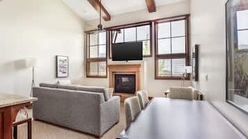 A living room with a fireplace, a large TV, and a dining area with a long table.