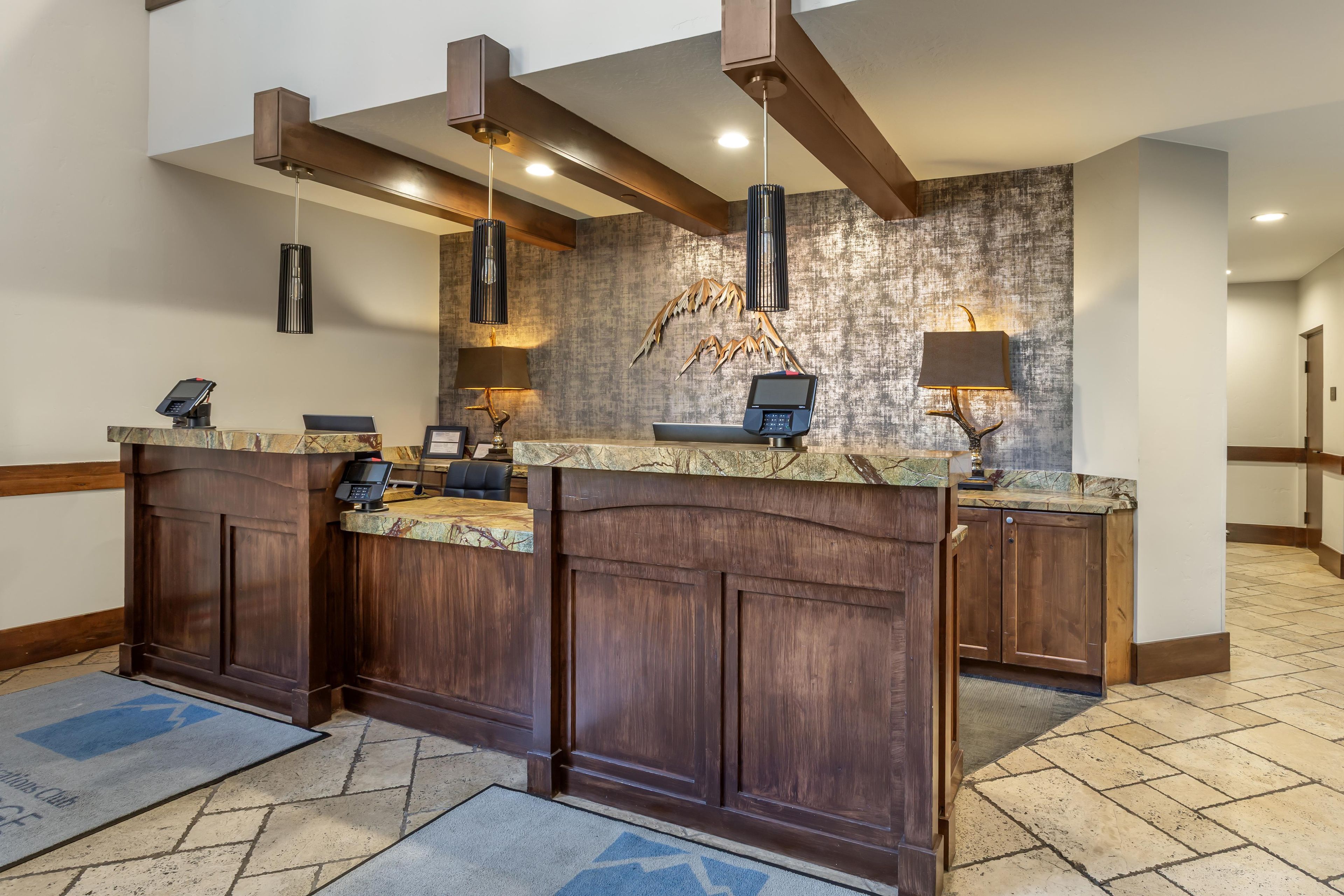 A reception area with a marble counter, wooden paneling, pendant lighting, and a textured wall.