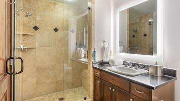 A modern bathroom with a glass-enclosed shower, a sink with a mirror above, and wooden cabinets.