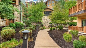 A pathway leading to a building with stone and wood exterior, surrounded by landscaped greenery. - Hilton Grand Vacations Club Sunrise Lodge Park City (Park City)