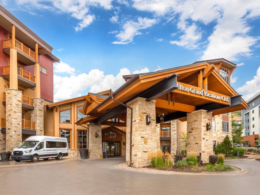 A hotel entrance with a covered walkway, stone pillars, and a sign for Hilton Grand Vacations Club.