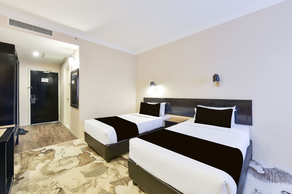 A hotel room with two beds, a desk, and a mirror.