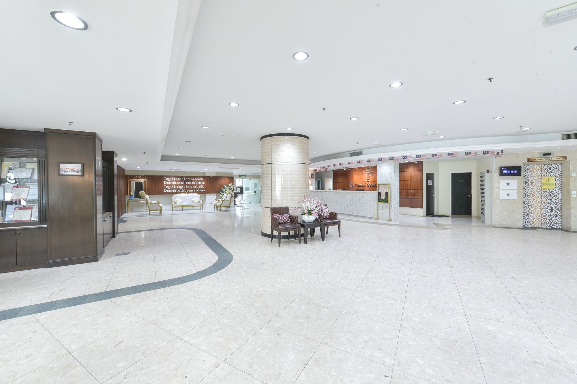 A spacious lobby with a reception desk, seating area, and a large pillar.