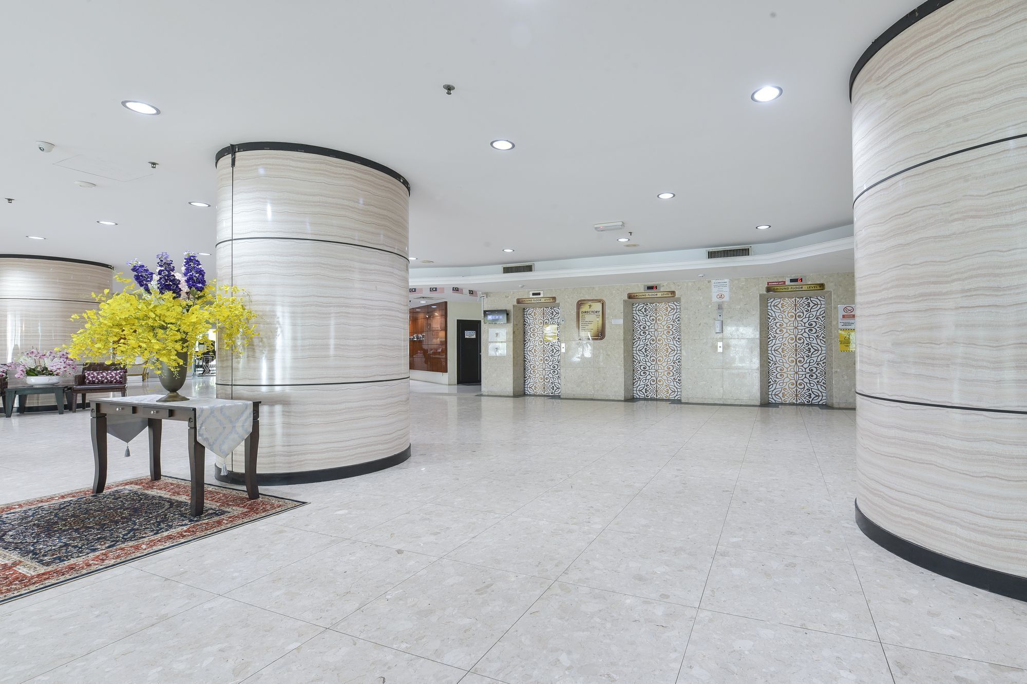 A spacious lobby with marble columns, a reception desk, and a directory wall.