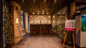 A reception area with a wooden ceiling, a reception desk, and a sign indicating safety assurance for ages 60+. - Regenta Inn Jaipur (Jaipur)