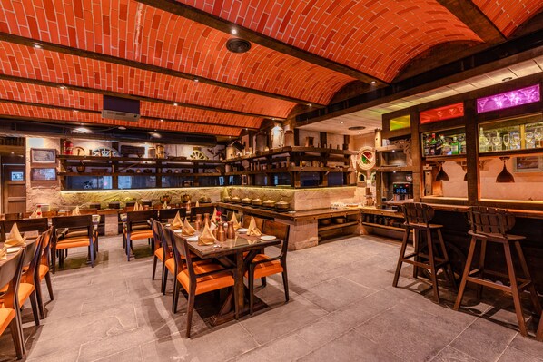 A restaurant with brick ceiling, wooden tables, and bar stools.