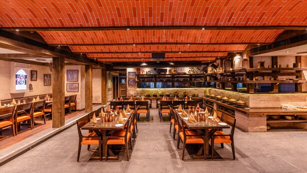 A restaurant with brick ceiling, wooden tables, and chairs. - Regenta Inn Jaipur (Jaipur)