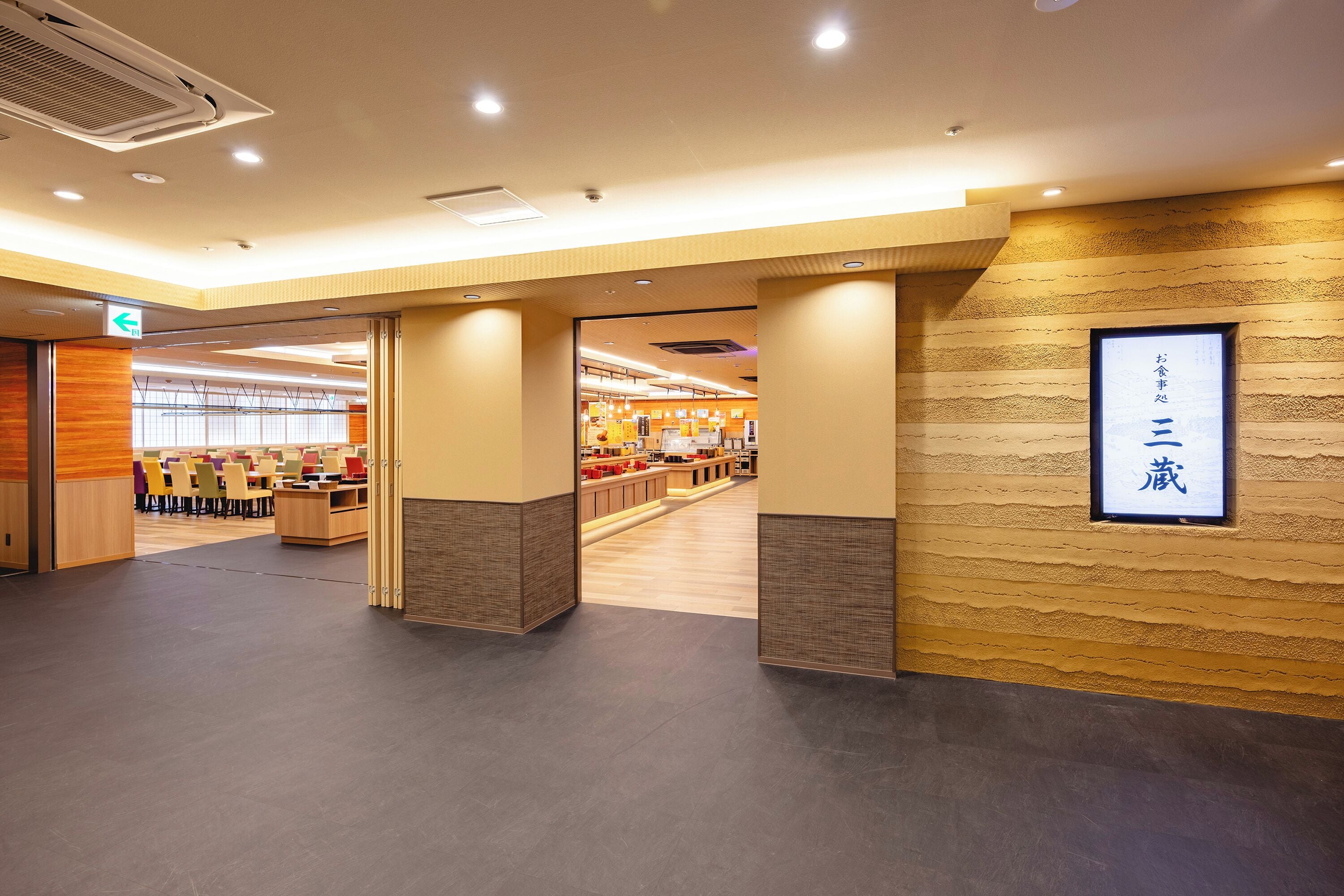 A hotel lobby with a reception desk, seating area, and a wall-mounted sign.