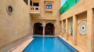 A swimming pool with ornate architecture and a clear sky.