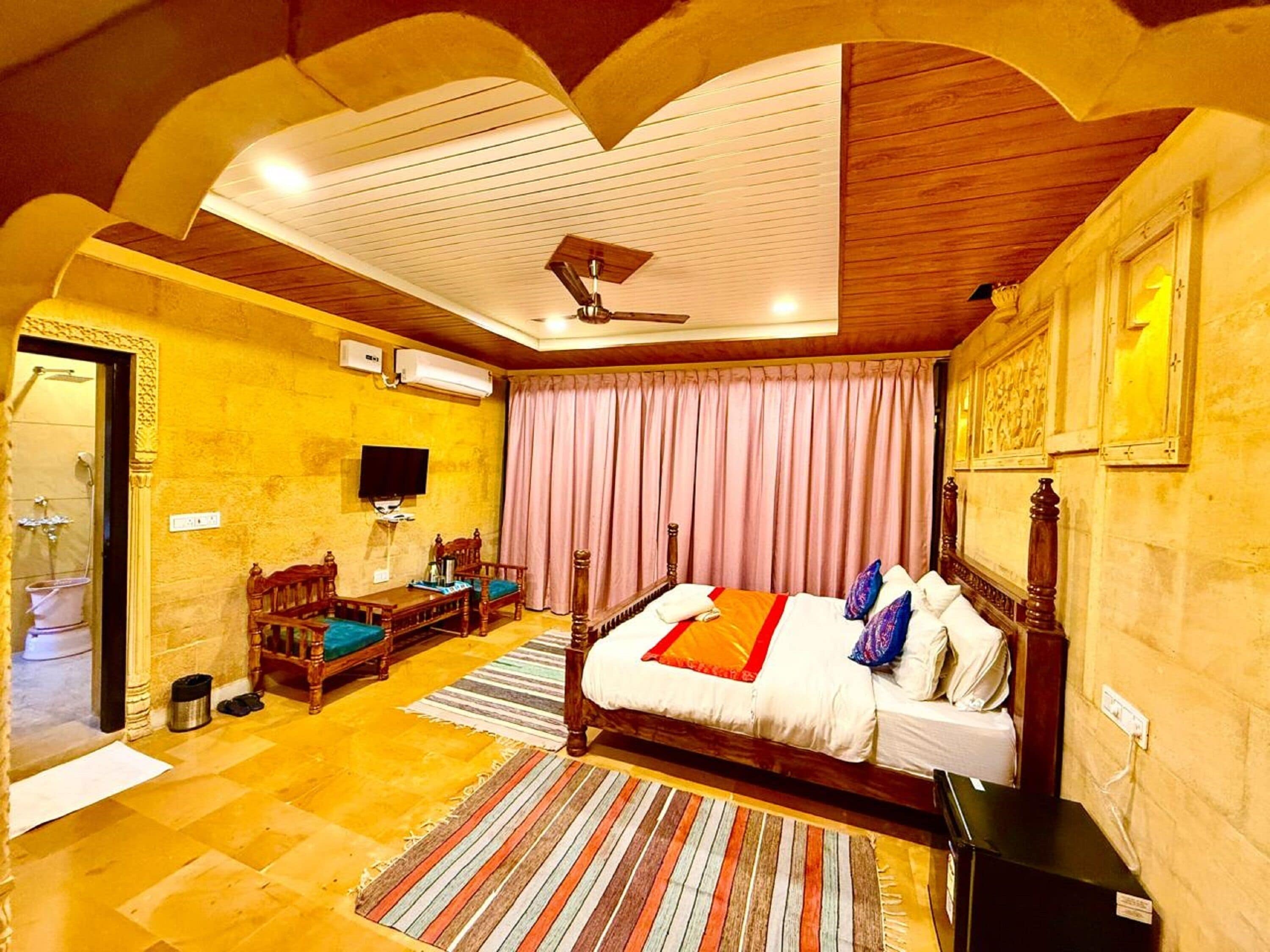 Une chambre d’hôtel avec un grand lit, une télévision, un ventilateur de plafond et une salle de bain équipée d’une douche et de toilettes.