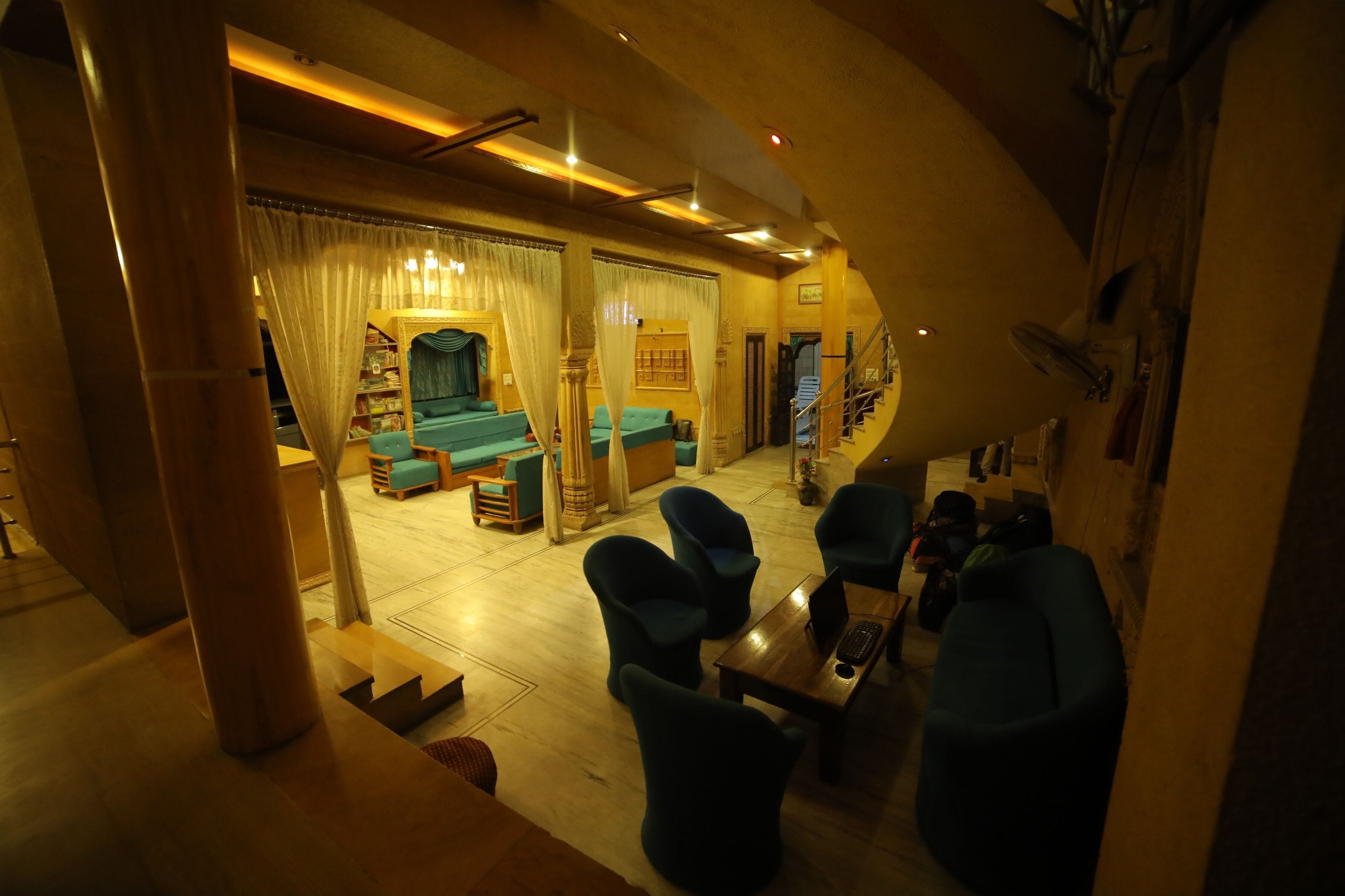 A spacious living area with a sofa set, a coffee table, and a laptop. There is a staircase leading to an upper level.