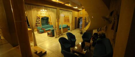 A spacious living area with a sofa set, a coffee table, and a laptop. There is a staircase leading to an upper level.