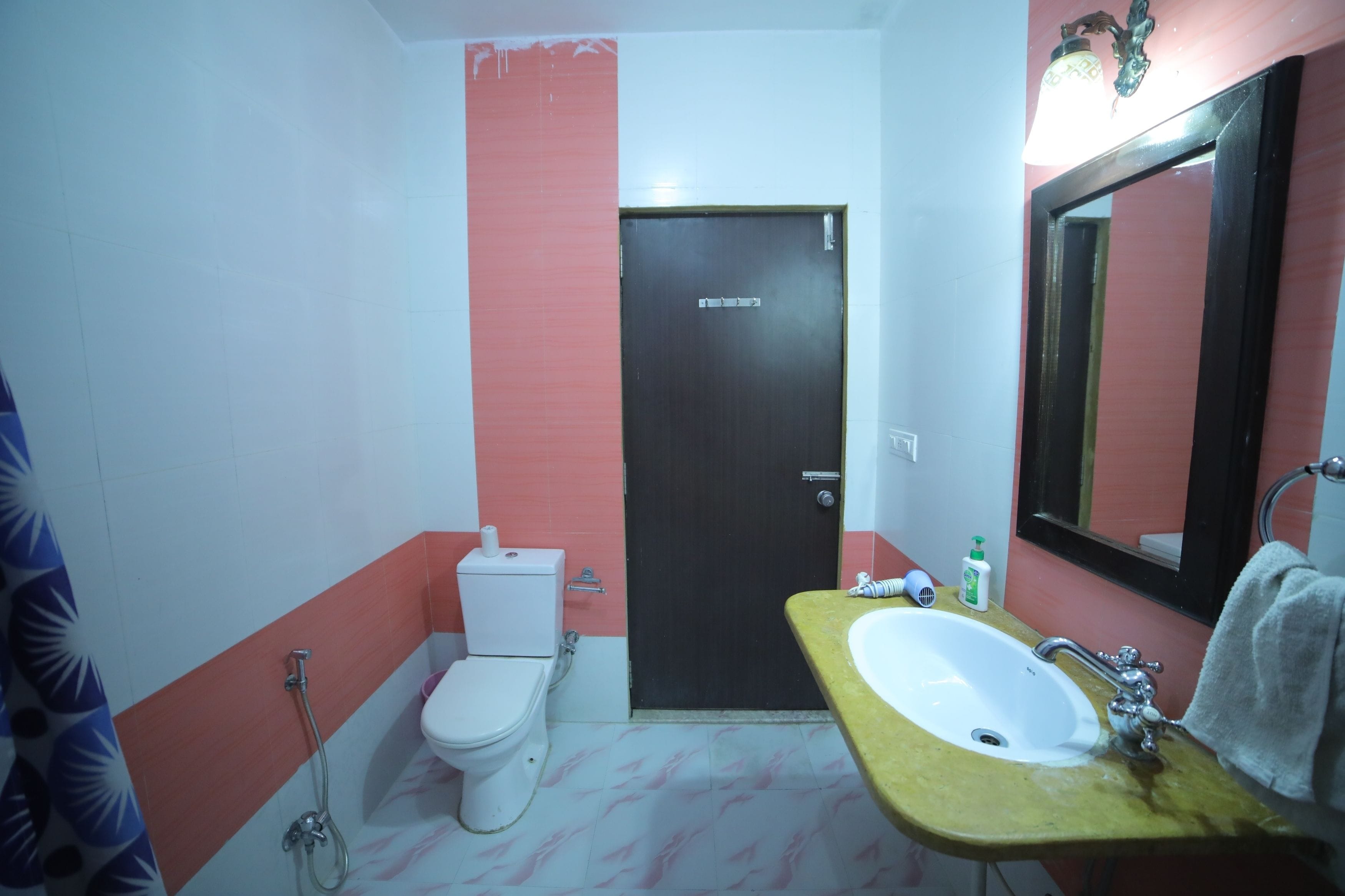 A bathroom with a toilet, sink, and mirror.
