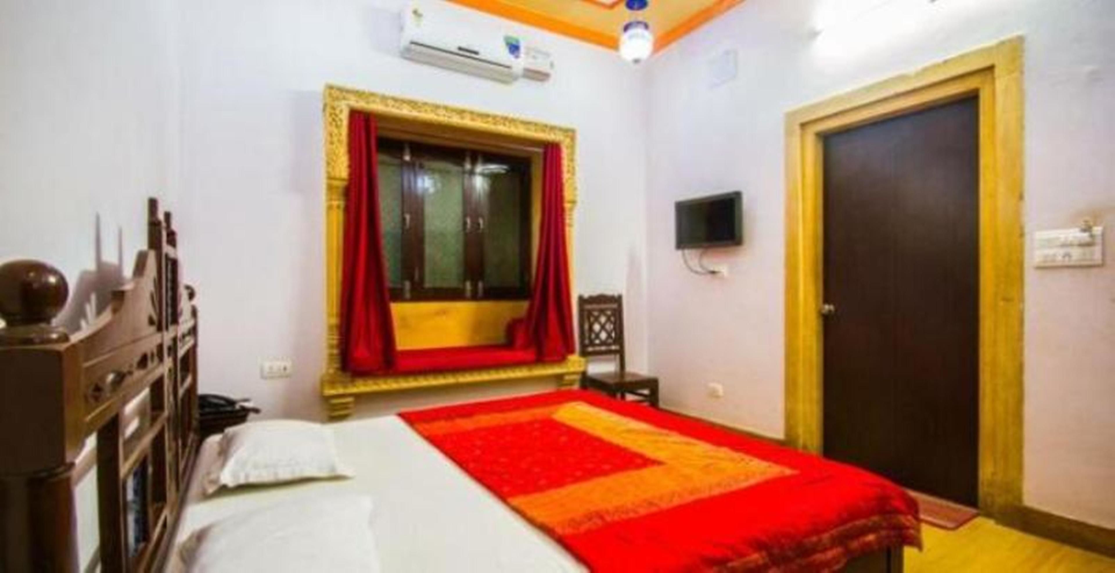 A bedroom with a bed, a wardrobe, a television, and a door.