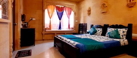 A bedroom with a bed, a nightstand, a window with curtains, a ceiling fan, and a wall-mounted shelf.