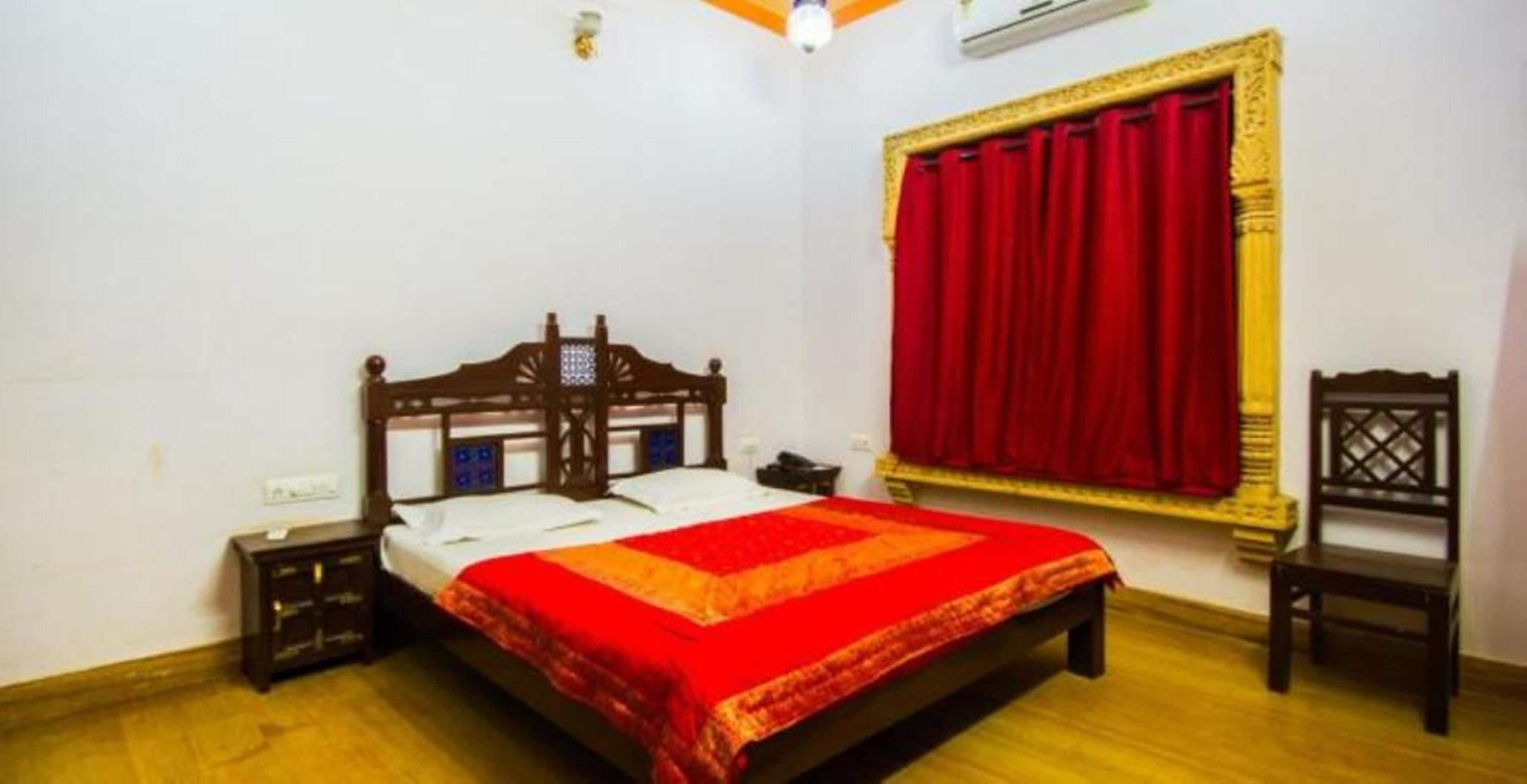 A bedroom with a wooden bed, a red curtain, a small nightstand, and a chair.