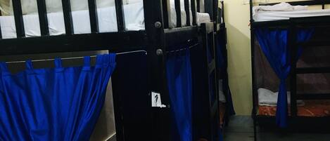 Quarto em dormitório com beliches, ventilador de teto, ar-condicionado e carpete estampado.