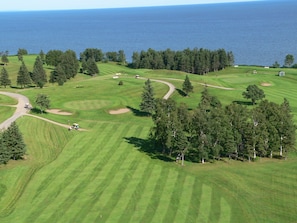 Vista aérea de un campo de golf con una gran masa de agua al fondo.
