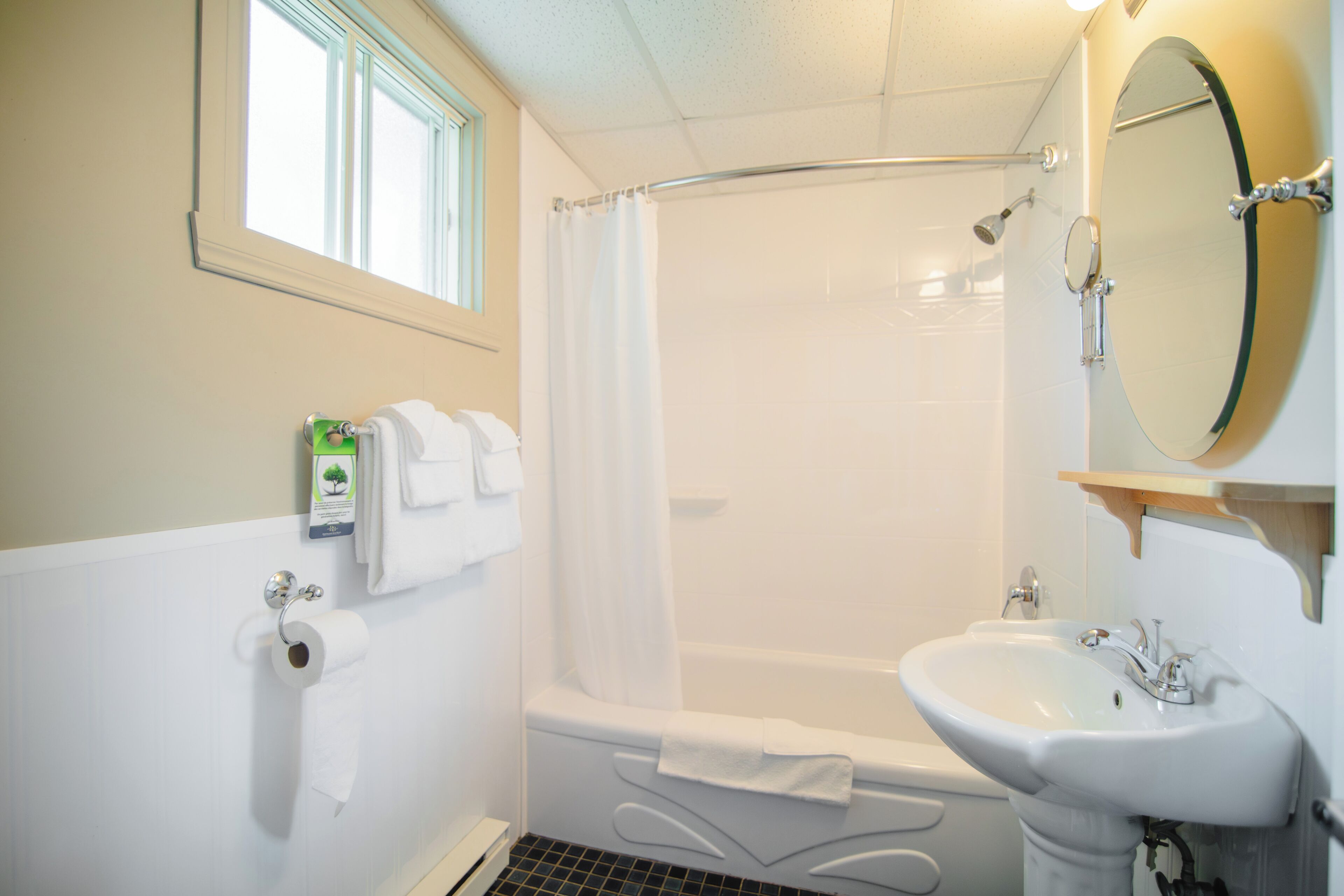 A bathroom with a bathtub, a sink, a shower, and a window.