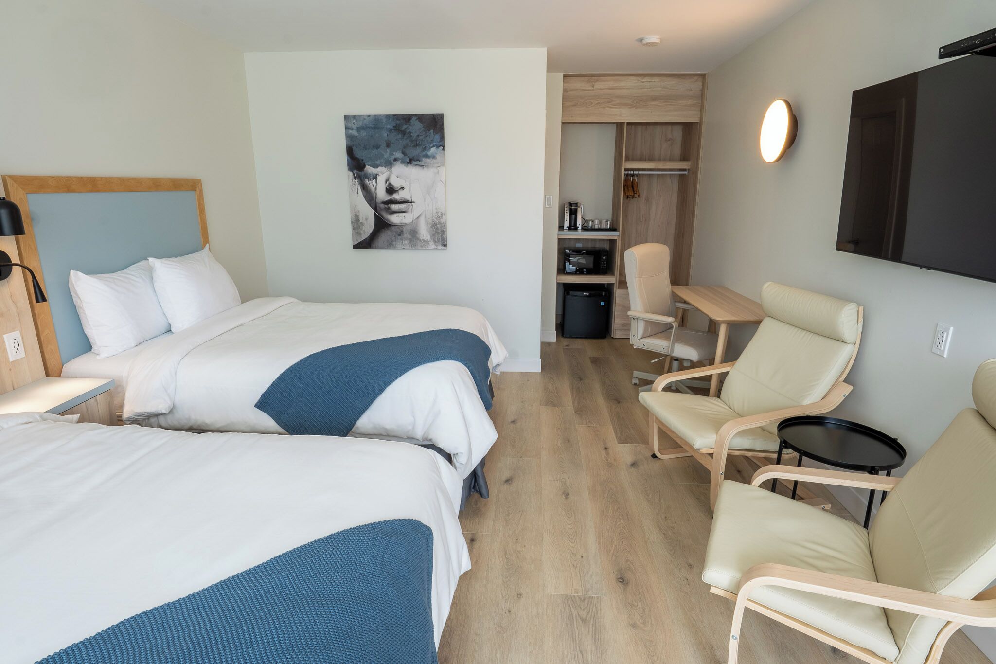 Une chambre d’hôtel avec deux lits, un bureau, une chaise, une télévision et une armoire.