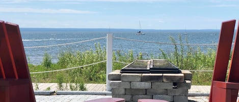 Une vue depuis un fauteuil rouge, donnant sur une étendue d’eau avec un voilier à l’horizon.