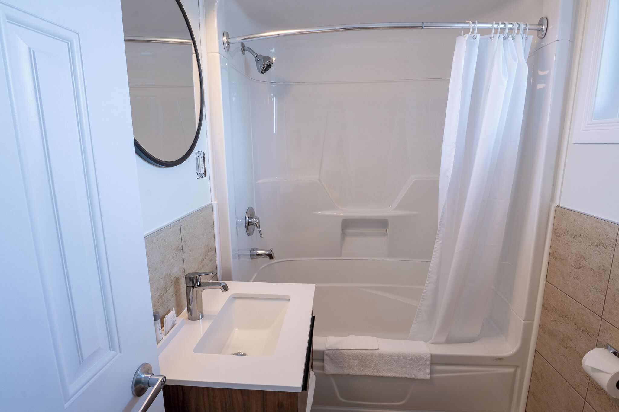 Un baño moderno con un lavamanos blanco, una ducha con cortina y un inodoro.
