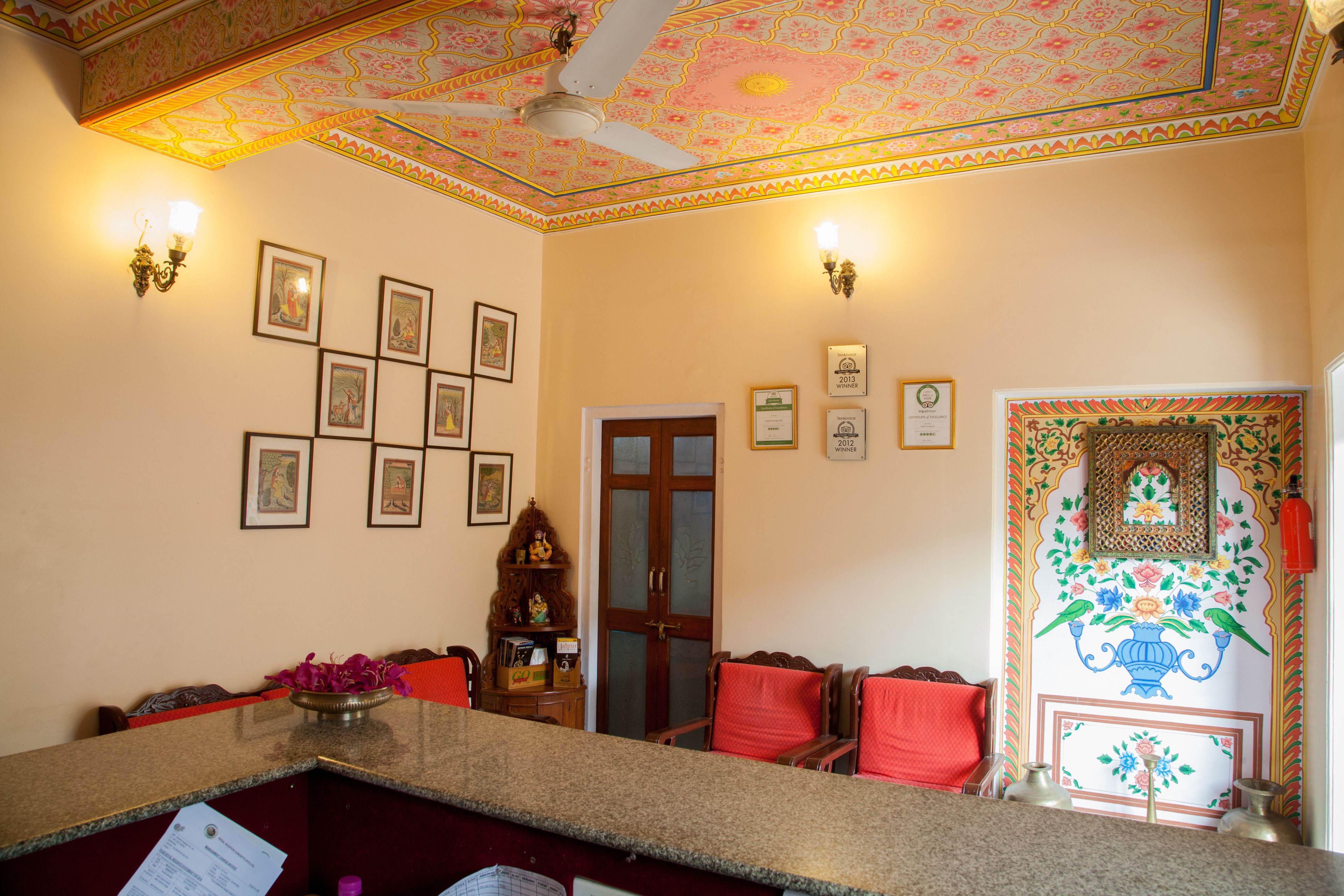 A reception area with a counter, framed pictures on the wall, and a decorative ceiling.