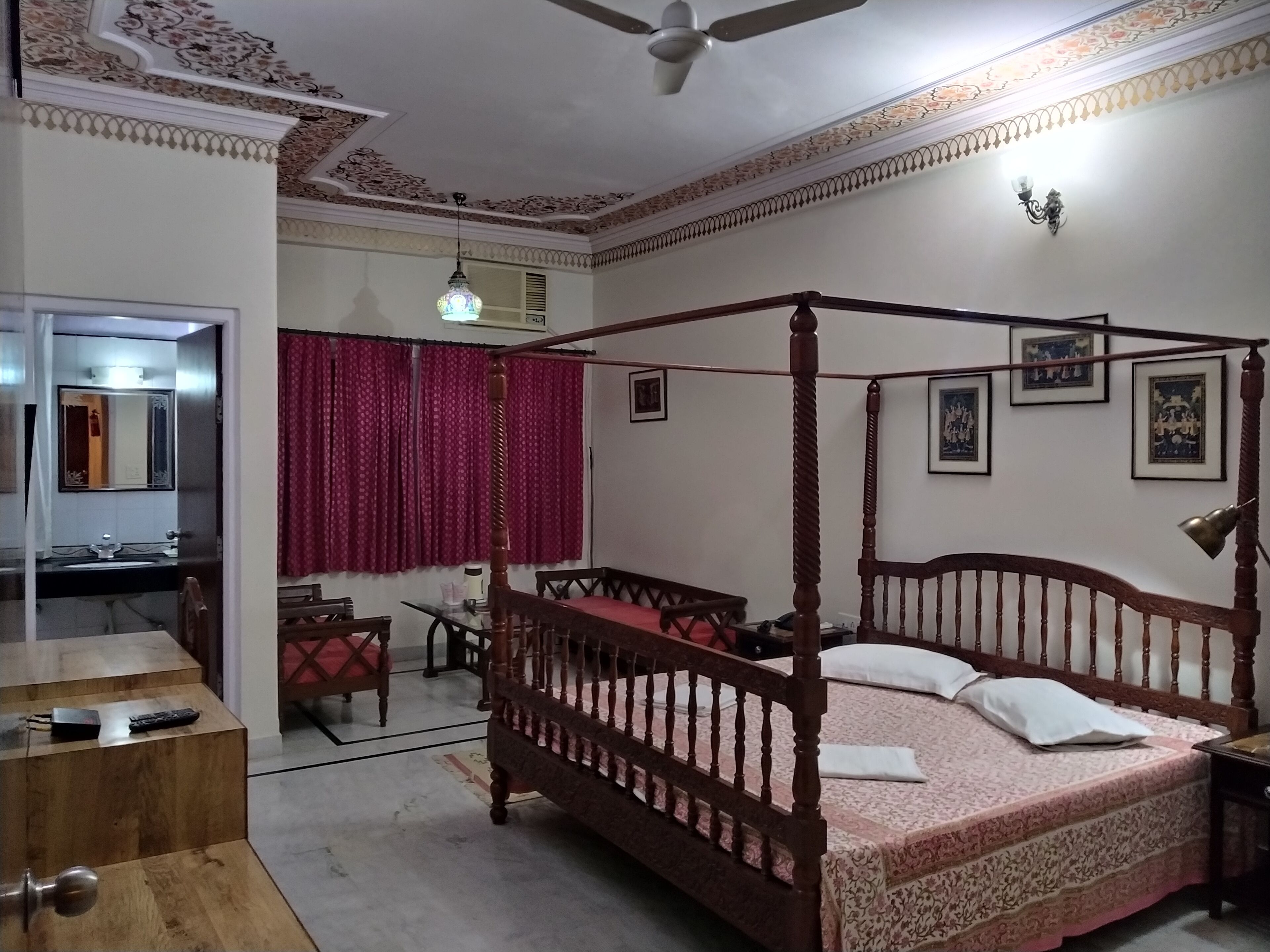Une chambre à coucher avec un lit à baldaquin, un bureau avec une chaise, une armoire et un miroir.