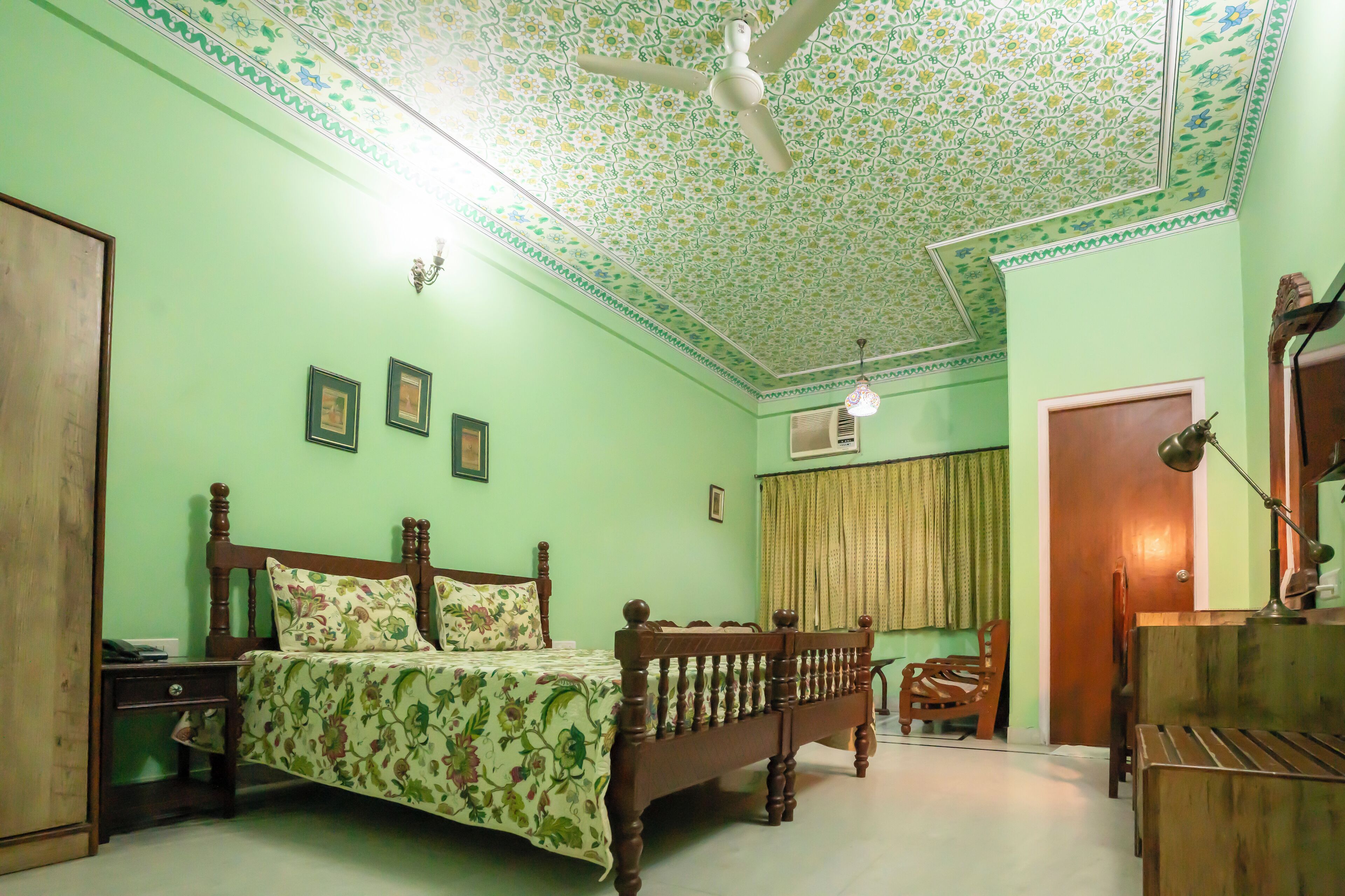 Une chambre à coucher avec un lit, des meubles en bois, un ventilateur de plafond et un plafond décoré de motifs.