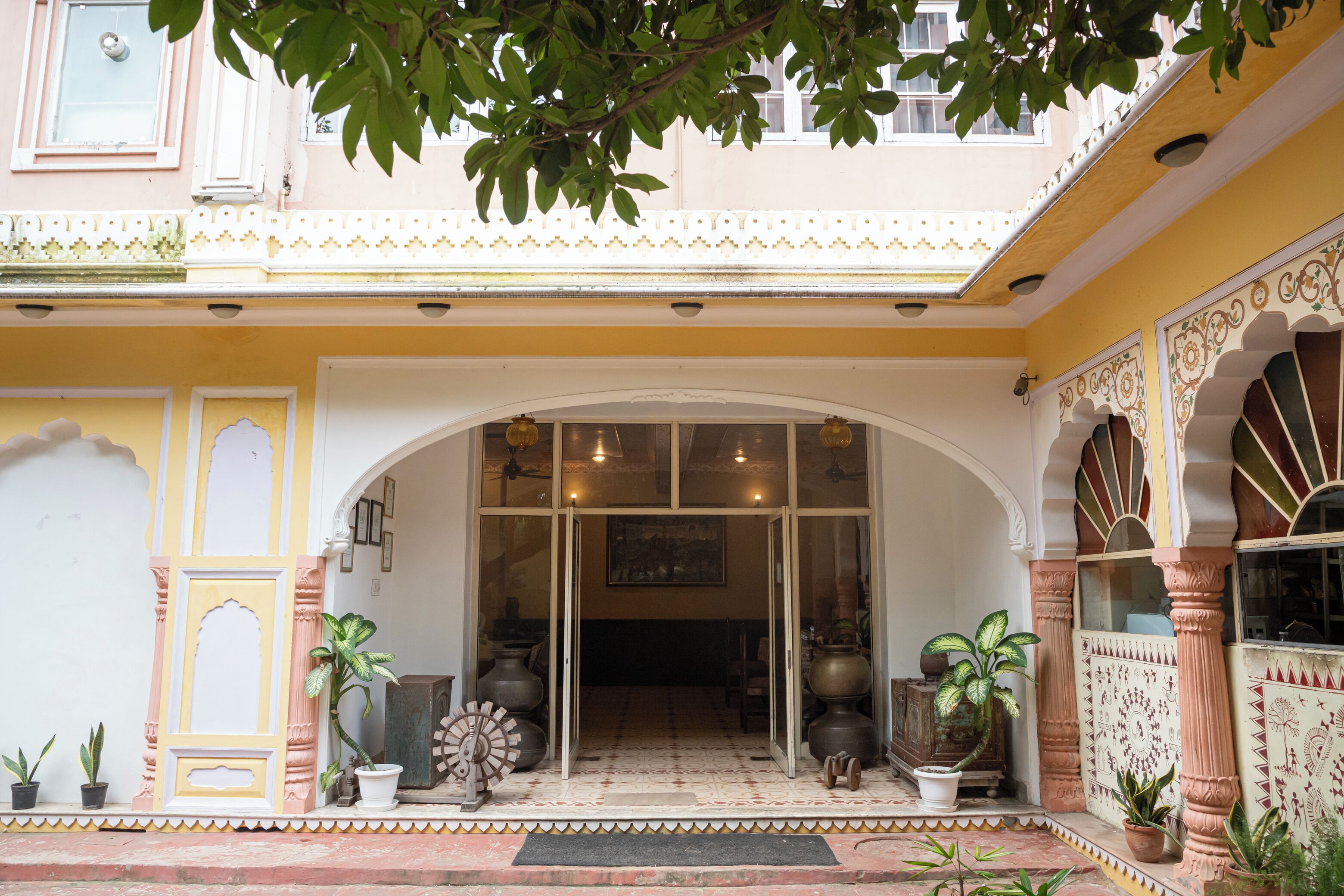 A traditional building entrance with an arched doorway, potted plants, and decorative vases.