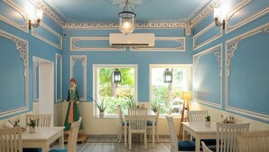 A room with blue walls, white furniture, and decorative moldings. There is a window with a view of greenery outside.